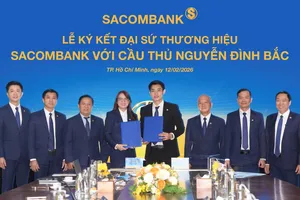 Cầu thủ Nguyễn Đình Bắc (phải) và bà Nguyễn Thị Kiều Anh (trái), Phó Tổng giám đốc SACOMBANK thực hiện nghi thức ký kết Thỏa thuận Đại sứ thương hiệu dưới sự chứng kiến của Ban lãnh đạo Ngân hàng