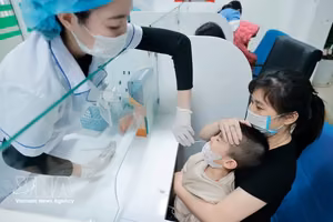 医务人员为患儿采集样本进行流感检测。图自越通社