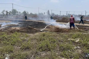 Lực lượng chức năng xã Tân Vĩnh Lộc đang khống chế đám cháy do các đối tượng đốt rác gây cháy lan tại khu đất trống trên đường Trần Hải Phụng, xã Tân Vĩnh Lộc. Ảnh: TK