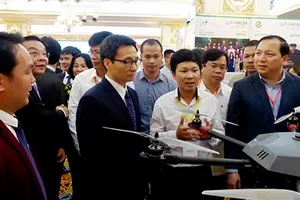 Phó Thủ tướng Vũ Đức Đam và lãnh đạo các bộ ngành tham quan, nghe giới thiệu về dự án thiết bị bay siêu nhẹ ứng dụng cho sản xuất nông nghiệp công nghệ cao. Ảnh: TRẦN BÌNH