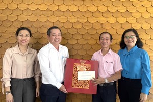 市委宣教与民运处副主任段文同该处干部向华人退休干部梁鸿德赠送新年礼物。