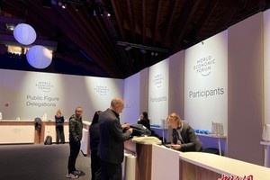 当地时间1月19日，世界经济论坛2026年年会在瑞士东部小镇达沃斯拉开帷幕。图为参会代表领取参会证件。