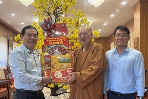 《西贡解放报》副总编辑阮玉英（左一）与采编部主任文忠孝（右一）向草堂禅寺住持释了明法师赠送贺年礼物。