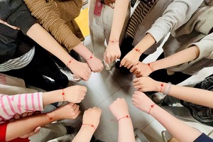 文郎大学中国语言专业学生展示亲手编织的相思子手链，体验七夕“乞巧”民俗文化。
