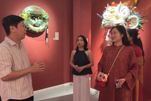 刘金钟与参观者交流，介绍展出的传统龙狮头。