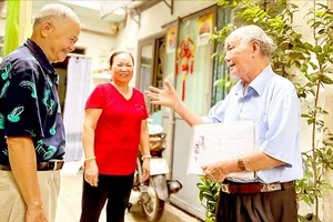 Ông Nguyễn Khắc Êm, nguyên tổ trưởng tổ dân phố 29, khu phố 3, phường Bến Nghé, quận 1 (TPHCM) trao đổi với người dân trong khu phố. Ảnh: THÁI PHƯƠNG