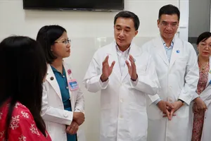 Thứ trưởng Bộ Y tế Trần Văn Thuấn trao tặng hoa và bằng khen cho ekip thực hiện ca can thiệp bào thai cho sản phụ người Singapore Ảnh: HOÀNG HÙNG