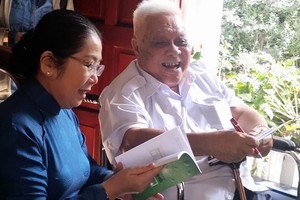 Professor Cao Minh Thi signs on a book to present to Ms. Dung  as a gift (Photo: SGGP)