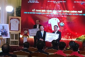Prime Minister Phuc (L) presents a gift to a leader of poor district (photo: SGGP)