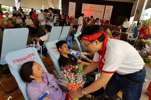 A member of the Red Journey's organising board presents flowers to a blood donor at the blood donation event in HCM City on June 22 (Photo: VNA)