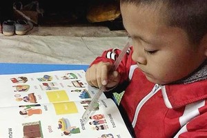 8-year-old Nguyen Thanh Dat  is reading his English book (Photo: SGGP)