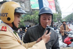 A traffic police officer takes an alcohol test for a motorcyclist. (Photo: VNA)
