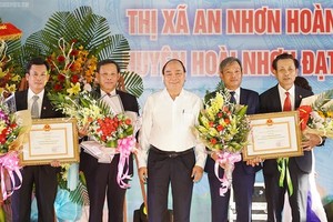 PM Phuc ( white) gives certificates to recognize the two communes to achieve the government's new rural plan (Photo: SGGP)