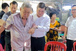 Chairman Phong leads resident Hai by the hand (Photo: SGGP)
