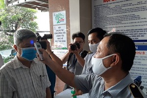 A medical worker measures temperature ofDeputy Health Minister Nguyen Truong Son (Photo: SGGP)