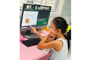 Second grader Pham Bao Thien Kim is taking part in an online lesson at home. (Phot: SGGP)