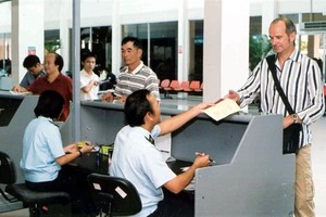 A customs official conducts immigration procedures for a foreigner at Tan Son Nhat airport in HCM City. — VNA/VNS Photo