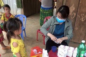 A medial worker is examining a etnic minority child in Dak Nong (Photo: SGGP)