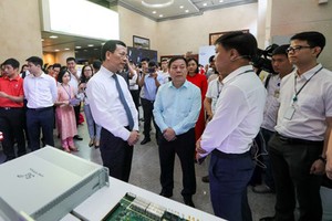 Minister of Information and Communications Nguyen Manh Hung paid a tour to ‘Make in Vietnam’ technological products in an exhibition in the framework of the conference. (Photo: SGGP)