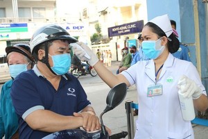 Relatives of patients are measured temperature before entering a hospital in HCMC (Photo: SGGP)