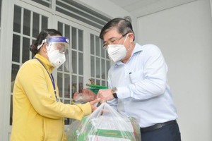 Chairman of HCMC People’s Committee Nguyen Thanh Phong delivers support packages to poor households in Nha Be District. (Photo: SGGP)