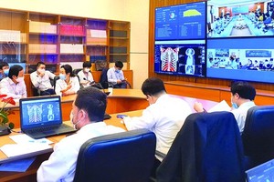 Doctors of Hanoi Medical University Hospital are discussing one Covid-19 case with their colleagues in lower-leveled hospitals. (Photo: SGGP)