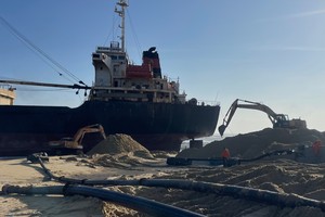 Dredge sand to save cargo ship stuck on coast