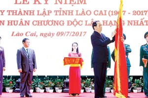 President Tran Dai Quang attaches the First class Independence Medal on traditional flag of Lao Cai province. 
