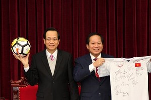 Minister of Labor - Invalids and Social Affairs Dao Ngoc Dung (left) and Minister of Information and Communications Truong Minh Tuan receive ball & football shirt of Vietnam U23 team offered to Prime Minister for auction.