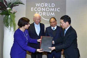 PM Nguyen Xuan Phuc (blue tie) and WEF Founder and Executive Chairman Klaus Schwab witness the signing of  an agreement between the WEF and Vietnam on building a centre for the Fourth Industrial Revolution. (Photo: VNA)
