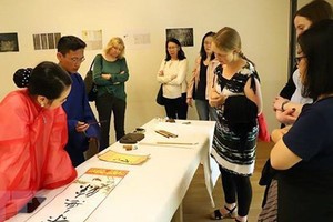 German and foreign tourists experience calligraphy performance at Vietnam Tag
