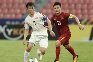 Team captains of Vietnam Nguyen Quang Hai (in red) and the DPRK Ri Chung-gyu vie for the ball (Photo: VNA)