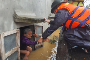 A rescue worker take an old woman out from her flooded house in Quang Binh Province (Photo: SGGP)