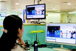 Nhân viên sân  bay kiểm tra thân nhiệt của hành khách trước khi nhập cảnh vào Việt Nam Ảnh: Hoàng Hùng