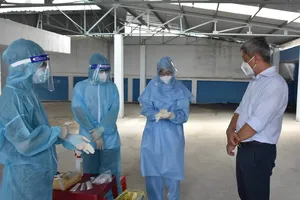 Thứ trưởng Bộ Y tế Nguyễn Trường Sơn thăm hỏi động viên nhân viên y tế lấy mẫu xét nghiệm cho người dân tại phường 25, quận Bình Thạnh.  Ảnh: KHÔI NGUYÊN