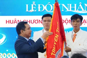 Chủ tịch UBND TPHCM Nguyễn Văn Được gắn Huân chương Lao động hạng Nhất lên cờ truyền thống Bệnh viện Răng Hàm Mặt TPHCM (Ảnh: HOÀNG HÙNG)