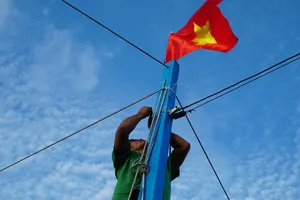  Ngư dân kiểm tra lại dây buộc Quốc kỳ trước khi cho tàu ra khơi. Ảnh: NLĐ                                                      