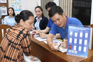 Cán bộ Trung tâm Phục vụ hành chính công phường Xóm Chiếu hỗ trợ người dân thực hiện thủ tục hành chính. Ảnh: THÁI PHƯƠNG