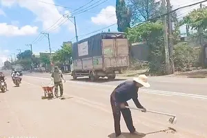 Đơn vị thi công và tài xế dọn dẹp đất, bùn sau khi lực lượng chức năng lập biên bản xử phạt. Ảnh: CSGT TPĐN