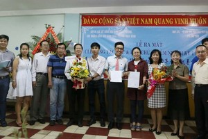 《西貢解放報》共青團書記阮祥欣（左六）和本報編委、編輯部主任范興（右一）遞交成立決定書和贈花祝賀。