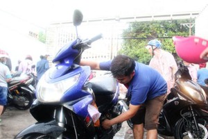 范如勝在雨中為路人免費修理車子。