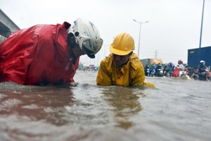 排水人員撬開河內公路迪哲橋附近路段的沙井蓋讓雨水排退。