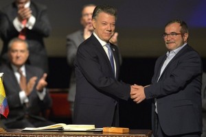 哥倫比亞總統桑托斯（左）和“哥武”領導人羅德里格·隆多尼奧·埃切韋里在新和平協議簽署儀式上握手。(圖源：互聯網)