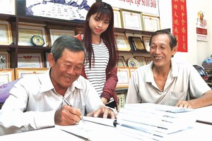 劉為安先生(左一)正在簽名贈書給文友。