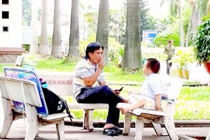 一病童家長在第二兒童醫院庭院裏對著孩子抽煙。