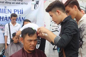 協兄邊給顧客理髮邊指導學員理髮手藝。