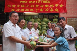 西貢左閭天后聖母廟會長李祺鏢(左一) 與理事們向貧困同胞贈送禮物。