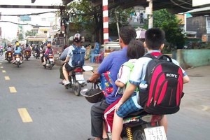 像這般既超載而自己及孩子都沒戴上安全帽的情景，在街上是司空見慣的。