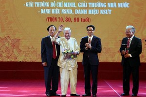 政府副總理武德膽（右二）向人民藝人、教授陳榜贈送鮮花祝賀。（圖源：廷南）