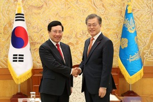 政府副總理、外長范平明（左）與韓國總統文在寅握手合影。（圖源：韓聯社）